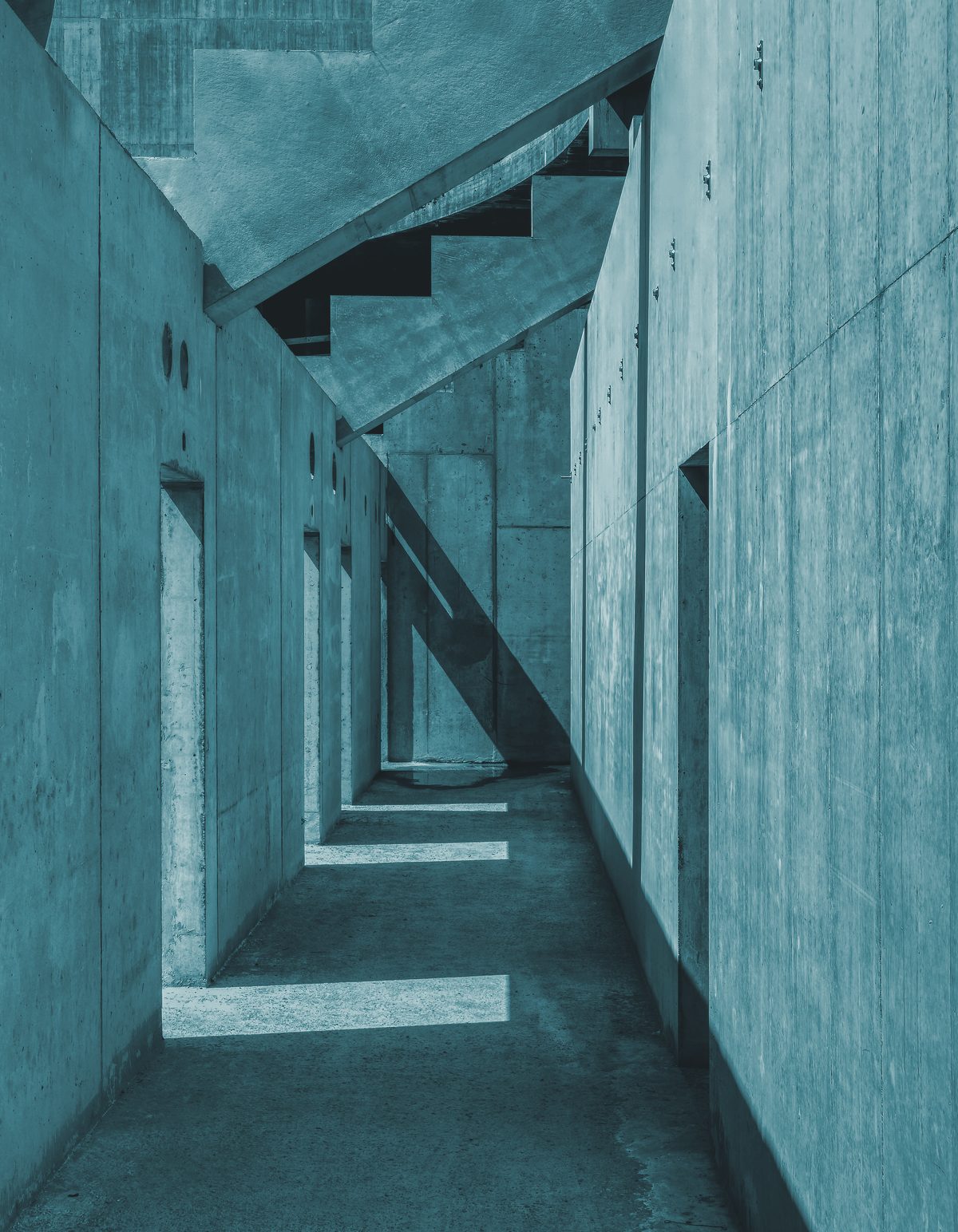 Couloir de béton en perspective, rythmé par des lignes verticales